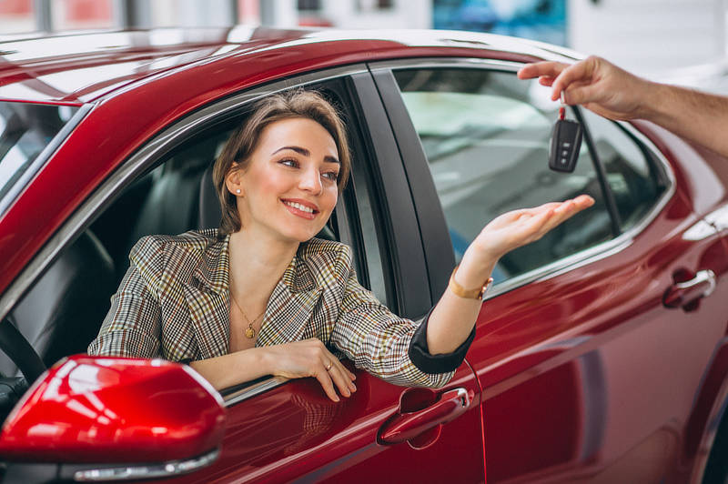Woman sitting in red car and receiving keys.