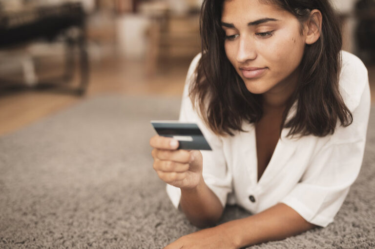Woman sitting on floor and looking at a credit card.