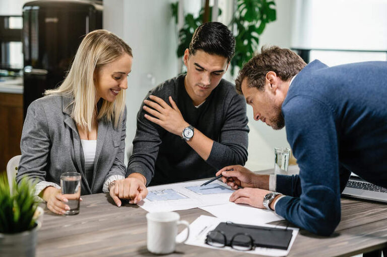 Real estate agent and young couple going through their housing plan on a meeting.