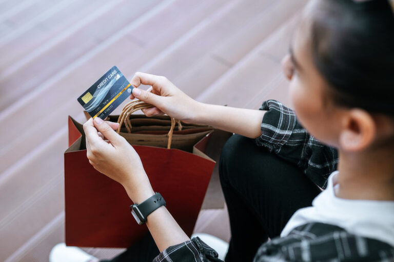 Young woman holding credit card in hand.