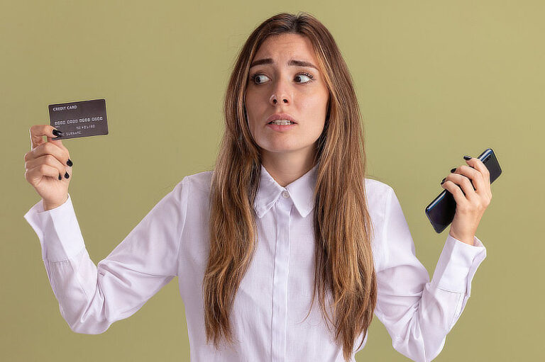 Girl holds phone and looks at credit card.